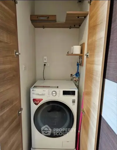 Compact laundry area with modern washing machine in a small storage space.