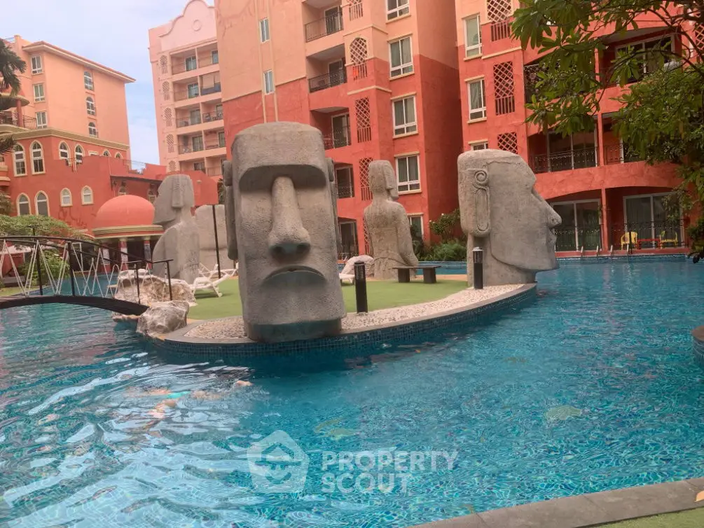 Luxurious apartment complex with unique poolside Moai statues and vibrant architecture.