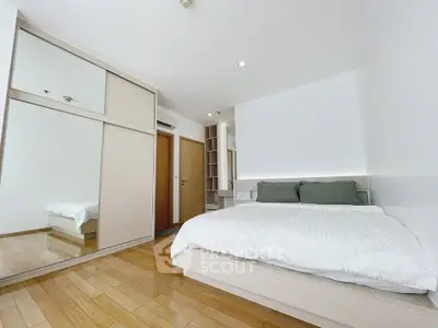 Spacious modern bedroom with wooden flooring and mirrored closet doors