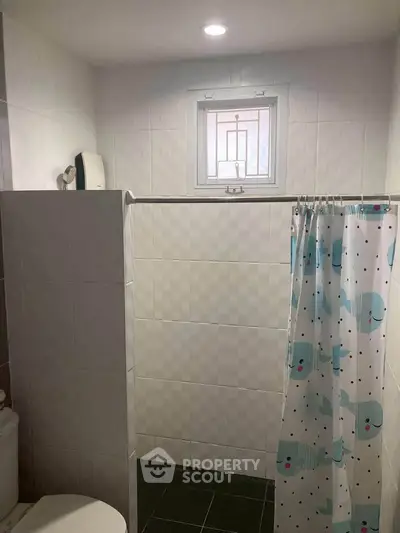 Cozy bathroom with tiled walls and playful shower curtain