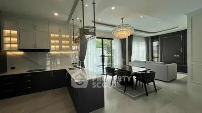 Luxurious open-layout kitchen and living room with elegant chandelier and modern design.