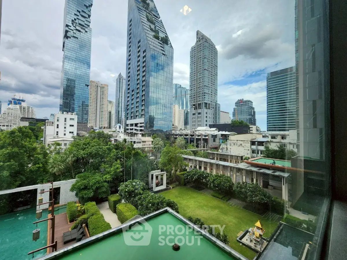 Stunning cityscape view from high-rise building with lush garden and pool area.