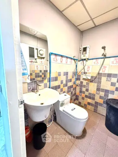 Compact bathroom with modern fixtures and colorful tile design, featuring a wall-mounted shower and sink.