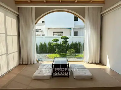 Elegant minimalist living room with large window and garden view, featuring traditional Japanese seating and wooden accents.