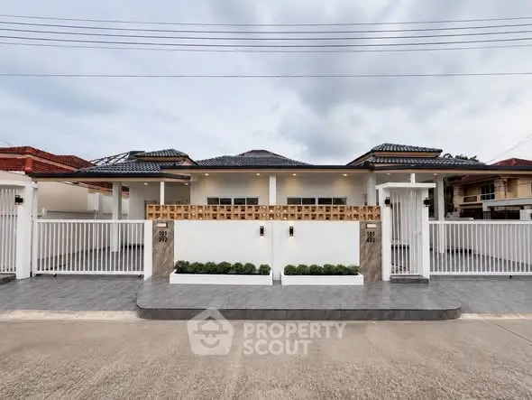 Modern single-story house with gated entrance and tiled driveway, showcasing contemporary architecture.