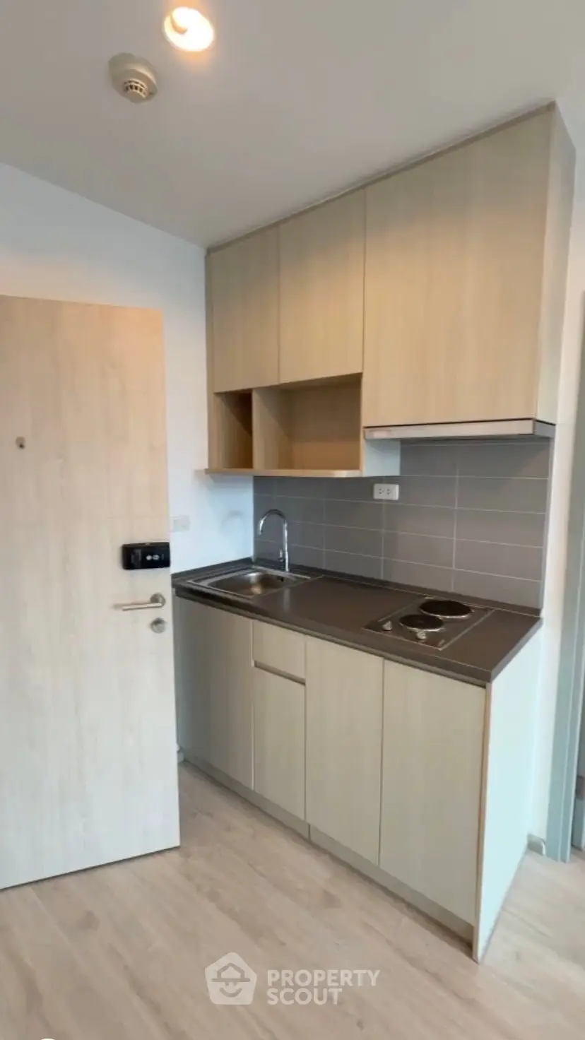 Modern compact kitchen with sleek cabinetry and electric stove in a stylish apartment.