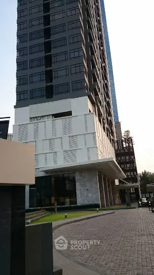 Modern high-rise building with unique architectural design and spacious entrance.
