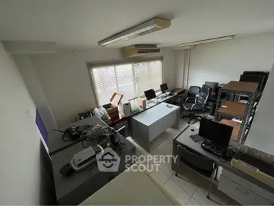 Spacious office room with desks, computers, and ample natural light from large window.