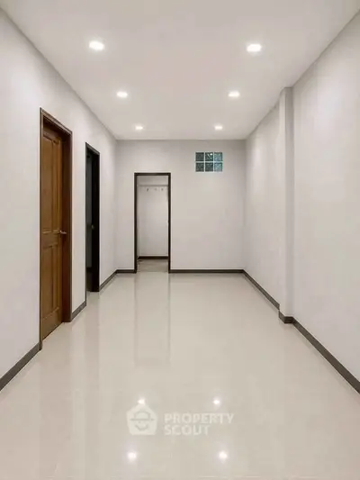 Spacious hallway with polished floors and modern lighting in a residential property.