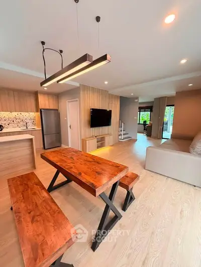 Modern open-plan living room with stylish wooden dining table and sleek kitchen, perfect for contemporary living.