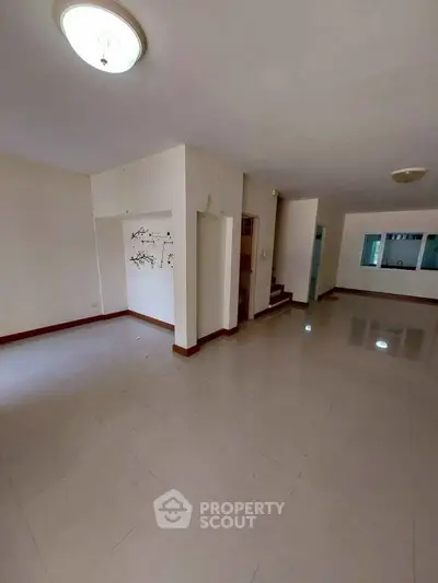 Spacious empty living room with glossy tiled floors and modern lighting, perfect for customization.