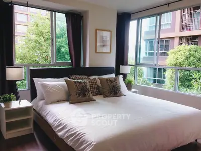 Spacious bedroom with large windows offering lush green views in modern apartment.