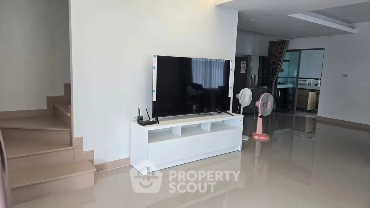 Spacious modern living room with sleek TV setup and glossy tiled flooring