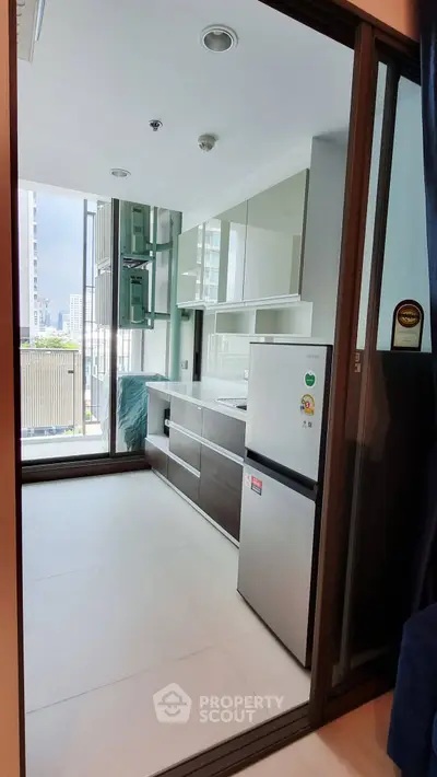 Modern kitchen with sleek cabinetry and balcony view in a high-rise apartment.