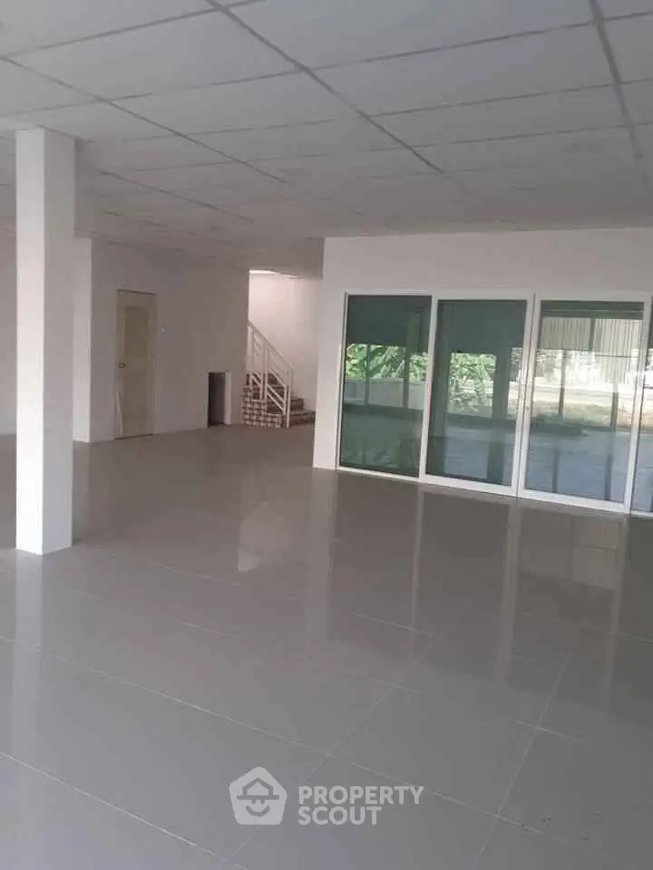 Spacious open-plan interior with tiled flooring and large windows, ideal for versatile living or office space.
