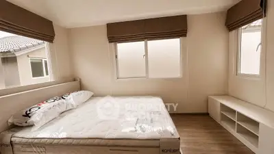 Modern bedroom with large windows and minimalist decor, featuring a comfortable bed and ample natural light.