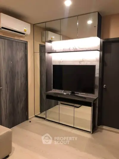 Modern living room with sleek TV unit and mirrored accents, featuring contemporary design and neutral tones.