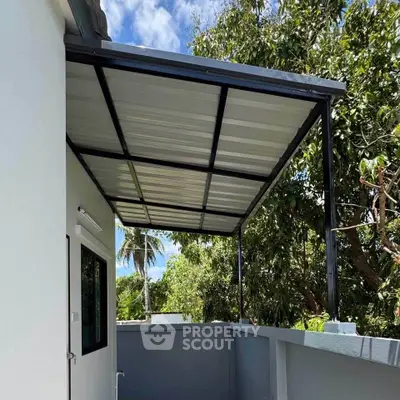 Modern balcony with metal roof and lush greenery view