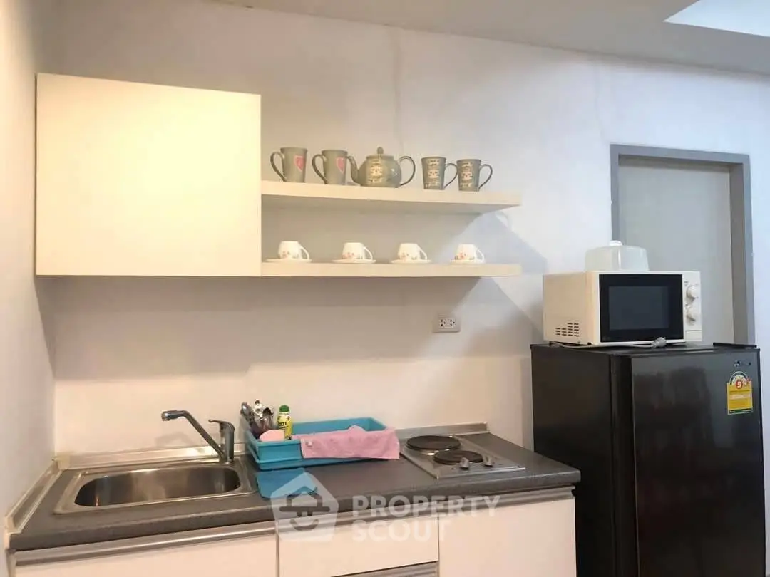 Compact kitchen with modern appliances and open shelving for stylish storage.