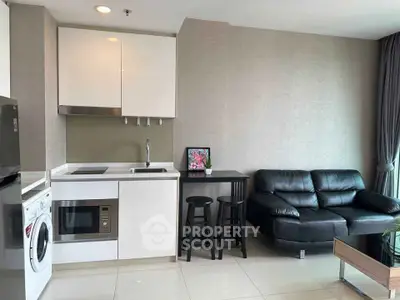 Modern open-layout living room with sleek kitchen and cozy seating area.