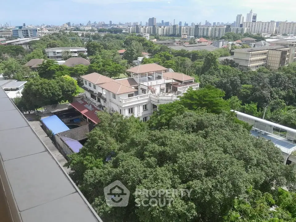 Stunning cityscape view from a high-rise building showcasing lush greenery and urban skyline.