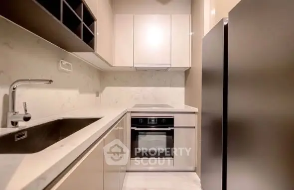 Modern kitchen with sleek cabinetry and built-in oven in a compact layout.
