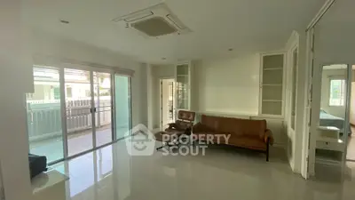Spacious living room with modern furniture and large windows leading to a balcony.