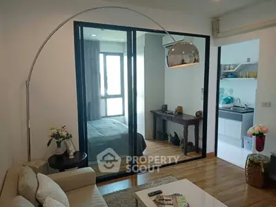 Modern living room with stylish decor and glass partition leading to bedroom