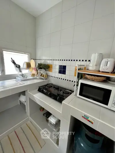 Charming kitchen with gas stove and microwave, featuring tiled walls and ample storage space.