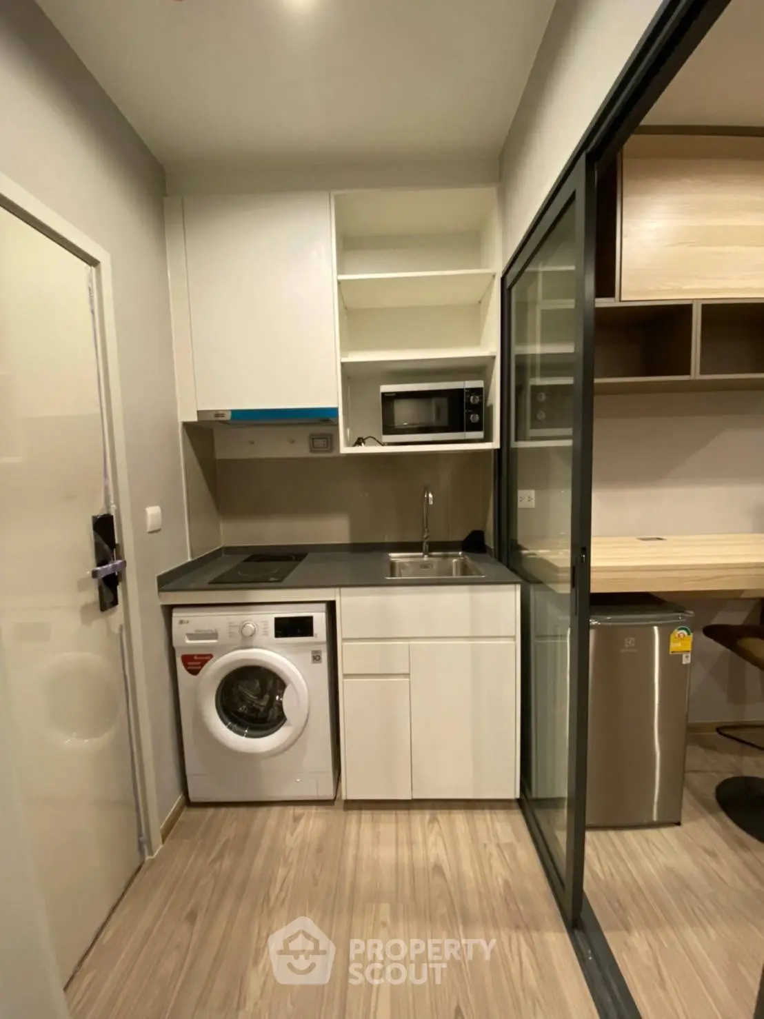 Modern compact kitchen with washing machine and microwave in sleek apartment