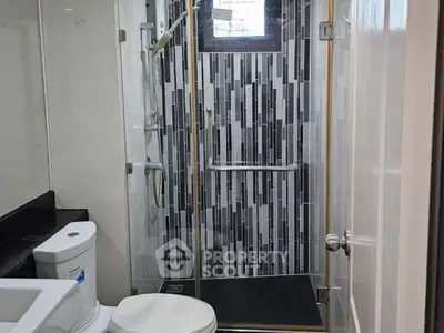 Modern bathroom with glass shower and sleek black and white tiles.