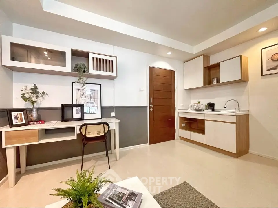 Modern studio apartment with stylish kitchen and study area, featuring sleek cabinetry and contemporary decor.