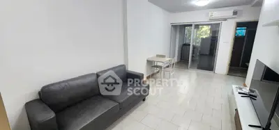 Modern living room with sleek gray sofa and minimalist decor, featuring a sliding glass door to a balcony.