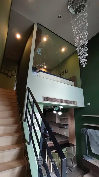 Modern loft apartment with stylish staircase and elegant chandelier, featuring a cozy mezzanine bedroom and open kitchen.