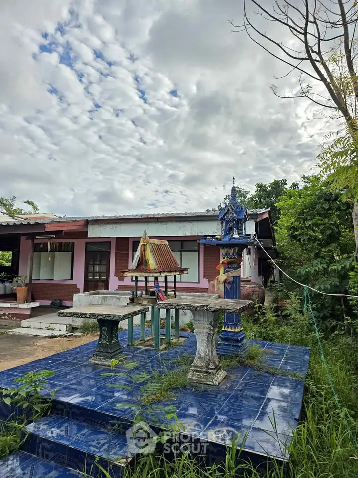 Charming single-story home with unique outdoor shrine and lush greenery.