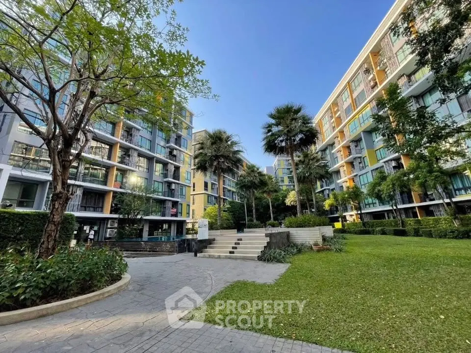 Modern apartment complex with lush garden and palm trees, perfect for urban living.