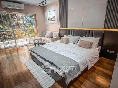 Luxurious bedroom with balcony and modern decor in a serene setting.
