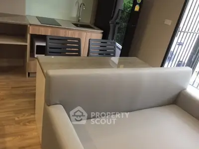 Modern apartment interior with sleek kitchen and cozy living area featuring a stylish sofa and dining table.