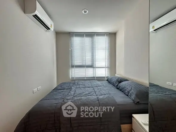 Modern bedroom with sleek design and natural light, featuring a comfortable bed and air conditioning.