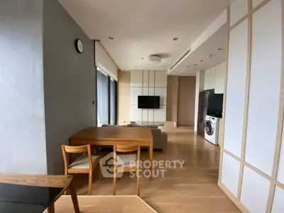 Modern living room with wooden flooring, dining table, and washing machine in a stylish apartment.
