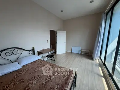 Spacious bedroom with large windows and elegant bed frame, offering ample natural light and modern decor.