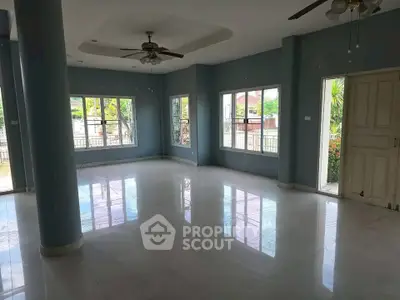 Spacious living room with large windows and ceiling fans in a modern home