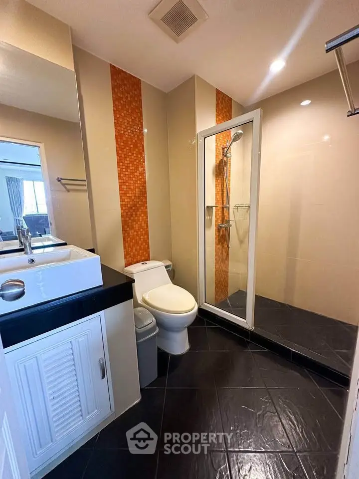 Modern bathroom with glass shower and stylish orange tile accents