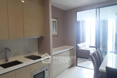 Modern kitchen with sleek cabinetry and open layout leading to a bright living area.
