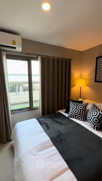 Cozy bedroom with modern decor and large window offering natural light.