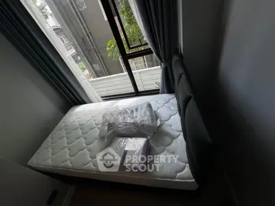 Cozy bedroom with large window and new mattress in modern apartment.