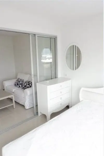 Bright and airy bedroom with sliding glass doors and modern white furniture.