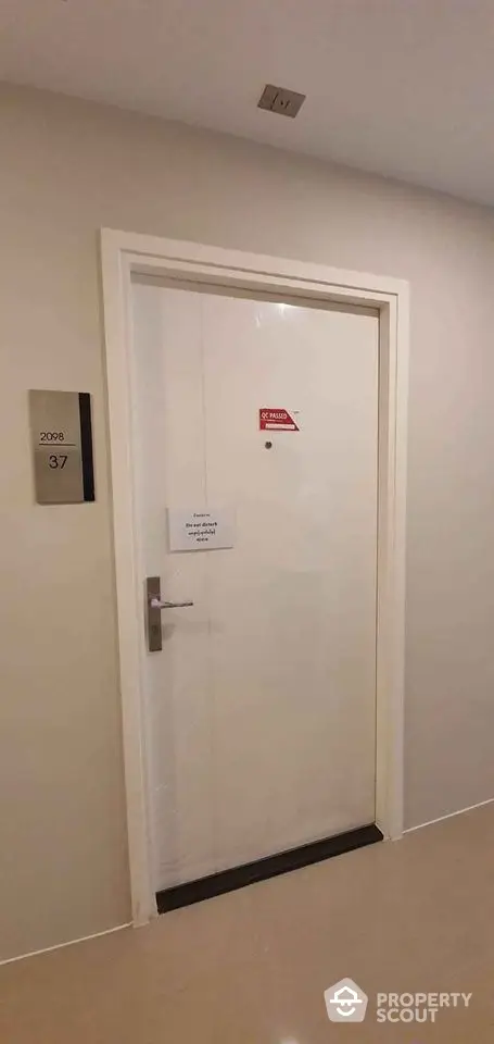 Modern apartment entrance with sleek white door and room number signage.