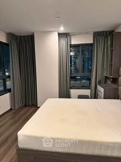 Modern bedroom with city view, featuring large windows and stylish furnishings.