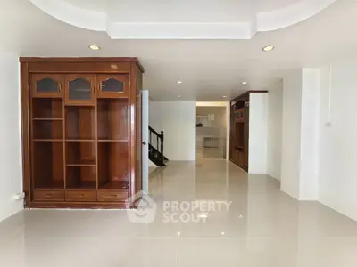 Spacious open-plan living area with elegant wooden cabinetry and glossy tiled flooring.